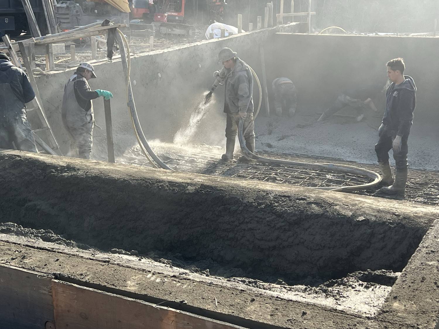 Construction workers spraying shotcrete onto rebar reinforcement during hot weather concrete placement in Ontario by CeMix Concrete Limited.
